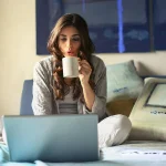 Seorang wanita menggunakan laptop di atas ranjang