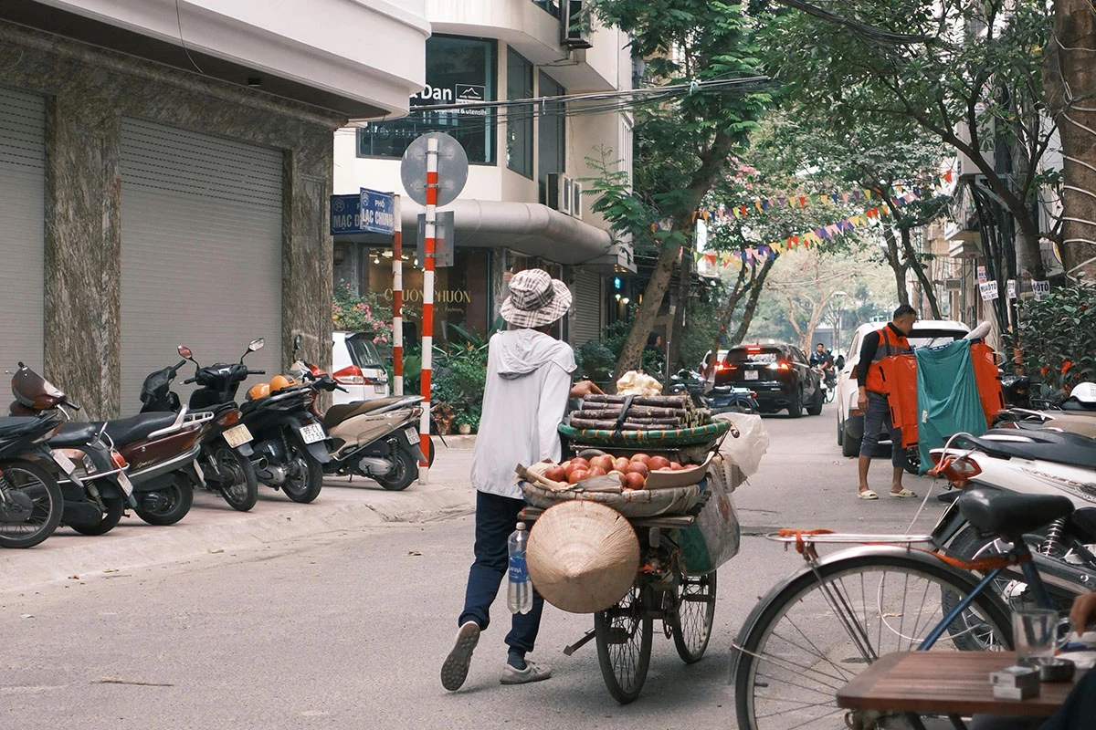 Seorang pria sedang mendorong sepeda sambil berjualan buah-buahan