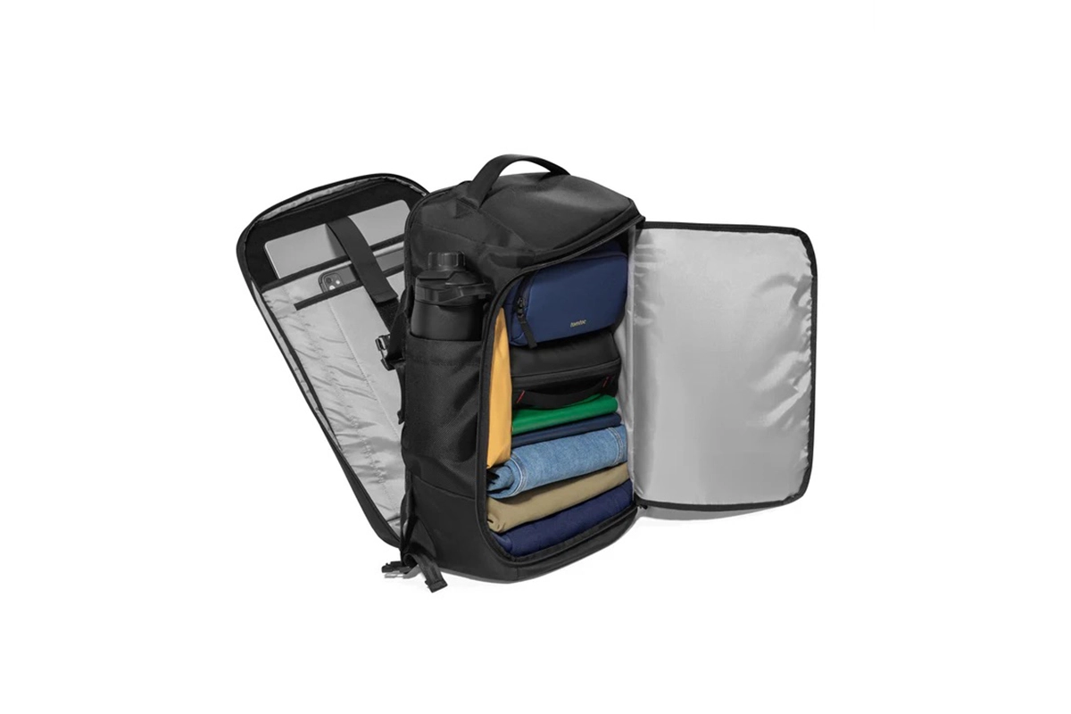 Tas travel Tomtoc Navigator T67 dalam posisi terbuka lebar (clamshell) menunjukkan kapasitas penyimpanan pakaian yang tersusun rapi, saku botol minum di samping, dan kompartemen laptop di bagian belakang.