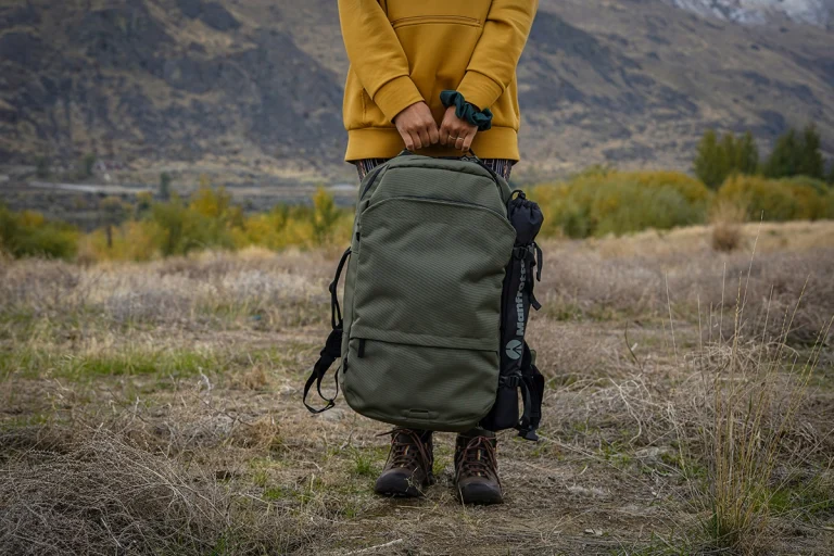 Woman wears yellow jacket holding a backpack